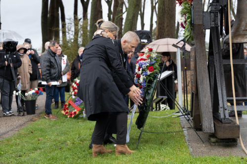 Burgemeester legt samen met zijn vrouw een bloemenkrans bij herdenkingsklok