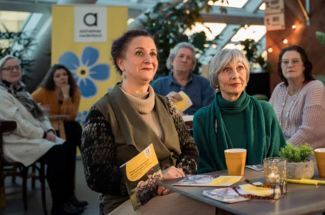 Mensen luisteren aandachtig tijdens een bijeenkomst van het Alzheimercafe